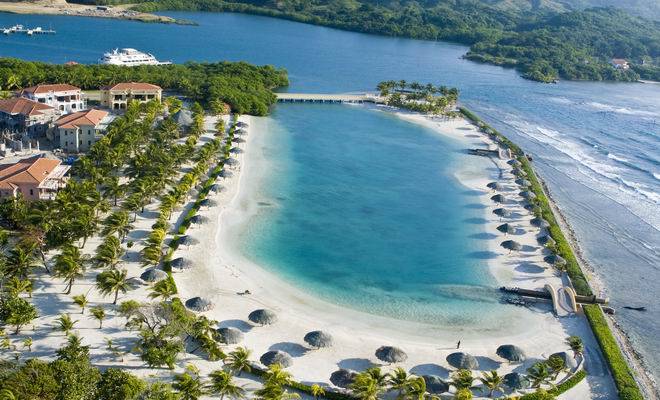 Aerial view of lagoon surrounded by palm trees and palapas, Roatan Honduras
